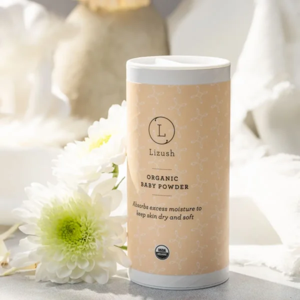 A tube of organic body powder sitting next to a flower.