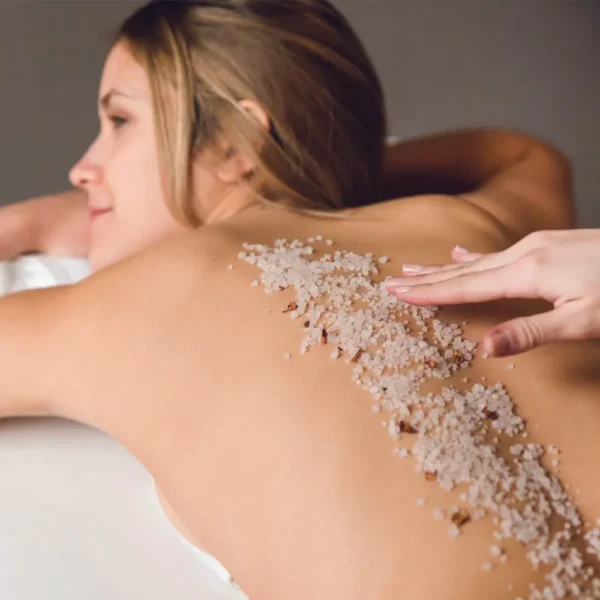 A woman is getting her back covered in salt.