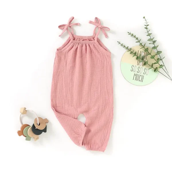 A pink baby girl 's jumpsuit with bow straps.